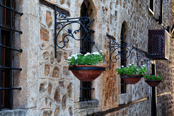Blooming flowers in a flower pot hanging from the wall near the window in the historical part of...