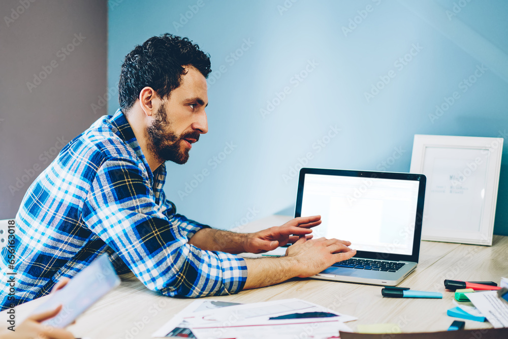 Poster serious male in casual wear using laptop computer with mock up screen showing new app for researchin