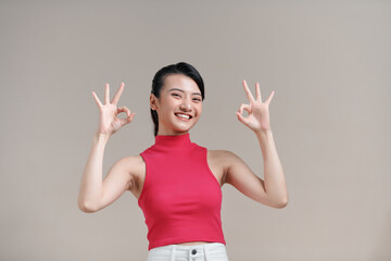 Young asian woman isolated on beige background cheerful and confident showing ok gesture.