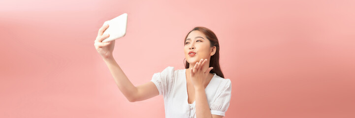 Young Asian girl using smartphone on pink background. Web banner