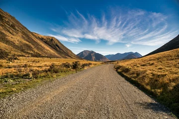 Foto op Canvas Rural gravel country road in the remote rural valley between the mountains and lakes © Stewart