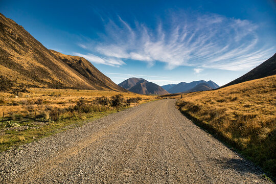 Rural gravel country road in the remote rural valley between the mountains and lakes