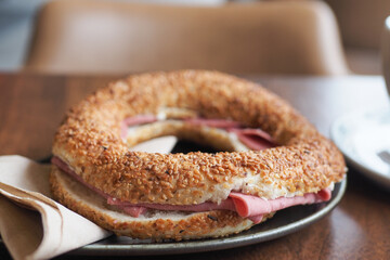 A bagel with tomato and salami on table 