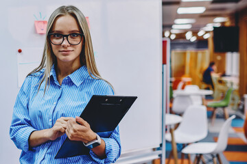 Attractive female teacher looking at camera before workshop in modern office