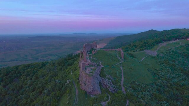 Aerial view of the ruins of a medieval citadel located in Siria, Arad county, Romania. Footage was done from a drone while flying forward above the ruins at sunset.