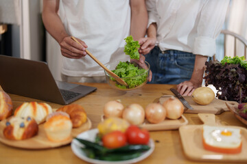 Couple making food or salad in the kitchen at home.