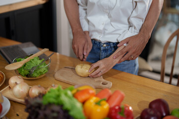 Couple cutting potatoes to cook or make salad in home kitchen.