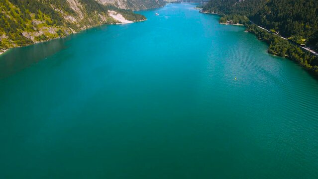 Aerial footage of the beautiful Achen Lake in Tyrol, Austria. Video of the lake was shoot from a drone while flying backwards lifting the camera to reveal the lake and the mountains in the background.