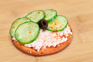 Crispy Cracker Sandwich with Fresh Cucumber, Fish Cream and Olives on Cutting Board. Easy...