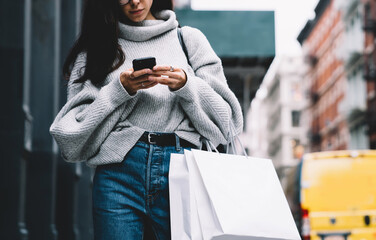 Trendy young woman browsing on mobile at street