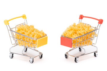 Uncooked Fusilli Pasta in Two Small Shopping Carts Isolated on White Background. A Crisis: Buying Cheap Food. Classic Dry Spiral Macaroni. Italian Culture and Cuisine. Raw Pasta - Isolation