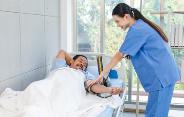 Asian professional experienced young female nurse in blue hospital uniform using wearing pressuring...