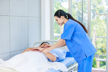 Asian professional experienced young female nurse in blue hospital uniform using wearing pressuring...