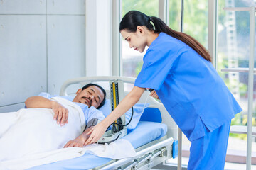 Asian professional experienced young female nurse in blue hospital uniform using wearing pressuring...
