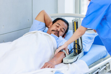 Asian professional experienced young female nurse in blue hospital uniform using wearing pressuring...