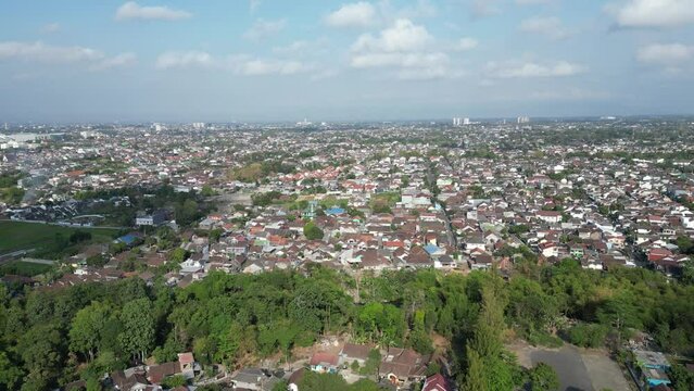 Aerial view of Jogja City with buildings, crowded vehicles traffic in morning sunlight. Sleman cityscape urban landscape. Population density is displacing agricultural land and forests.