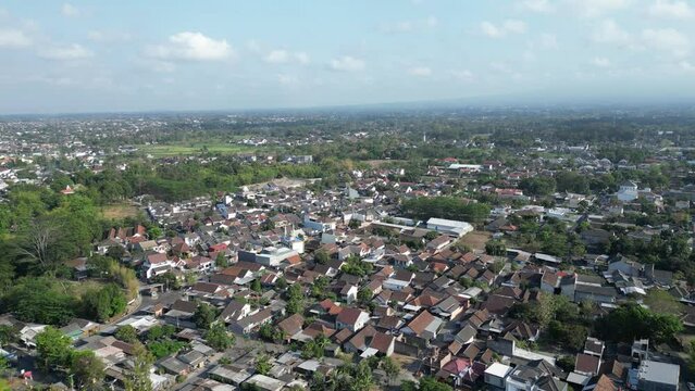 Aerial view of Jogja City with buildings, crowded vehicles traffic in morning sunlight. Sleman cityscape urban landscape. Population density is displacing agricultural land and forests.