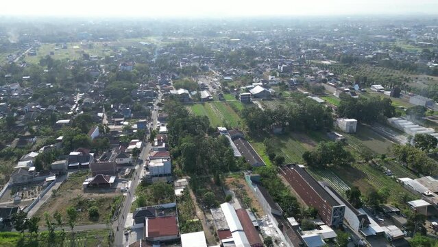 Aerial view of Jogja City with buildings, crowded vehicles traffic in morning sunlight. Sleman cityscape urban landscape. Population density is displacing agricultural land and forests.