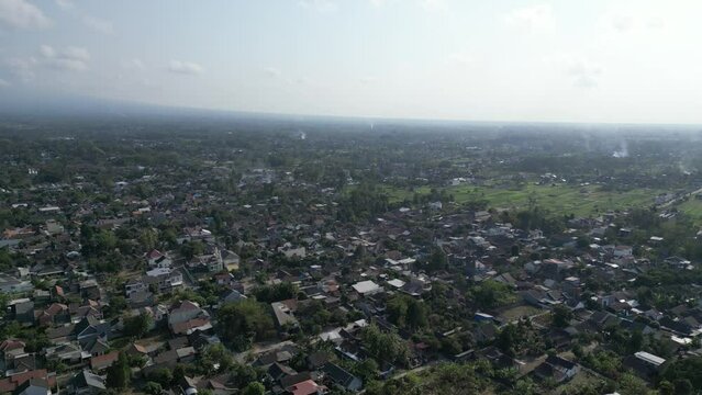 Aerial view of Jogja City with buildings, crowded vehicles traffic in morning sunlight. Sleman cityscape urban landscape. Population density is displacing agricultural land and forests.