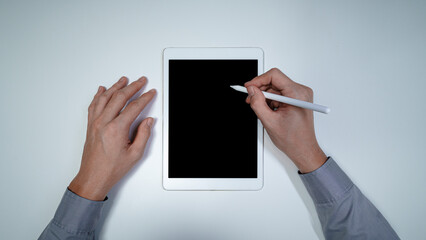 Businessman top view hands holding black screen ipad touchpad mockup for website or application writing and taking note using pen showing media display advert information in corporate workplace table - obrazy, fototapety, plakaty