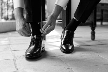 Novio poniendose los zapatos y atandose los antes de la boda