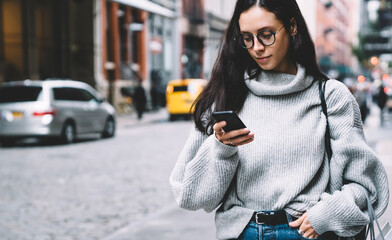 Woman browsing smartphone while walking down street