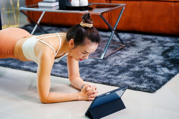Portrait of cheerful healthy sporty fitness Asian woman doing yoga shoulder stretching in living...