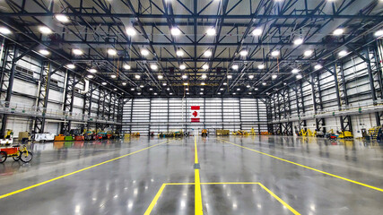 An aircraft hangar sits empty with a well lit Canadian flag in the background turned on its side