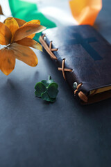 A leather-bound Bible on the table. Religious Christian Irish celebration. Four-leaf clover symbol...