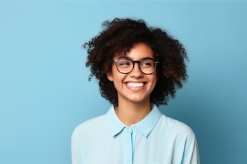 Portrait of a happy young african american woman in eyeglasses on blue background - obrazy, fototapety, plakaty