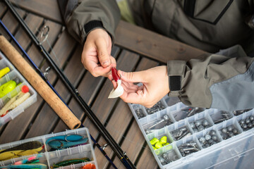 a man threads a fishing hook into a rubber bait, fishing, spinning, preparation for fishing,...