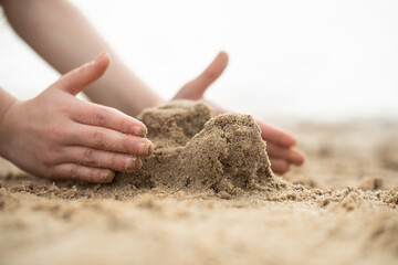 A girl plays with sand, a girl builds a castle from sand