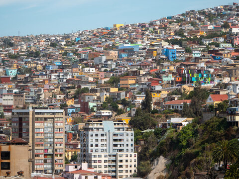 The art deco city of Valparaiso Chile houses stand crowded along a hillside brightly painted in different colours. 