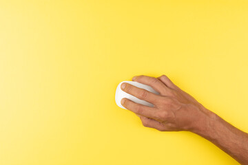 black male hand with white computer wireless mouse on isolated yellow - obrazy, fototapety, plakaty