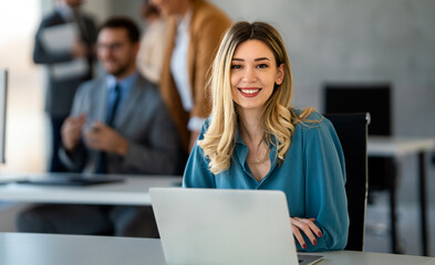 Successful young attractive businesswoman working on laptop in her workstation at office