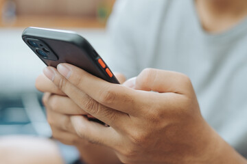 Hands of Asian man holding checking touching scrolling smartphone from bed room