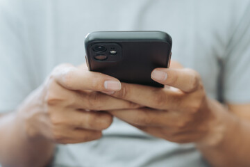 Hands of Asian man holding checking touching scrolling smartphone from bed room