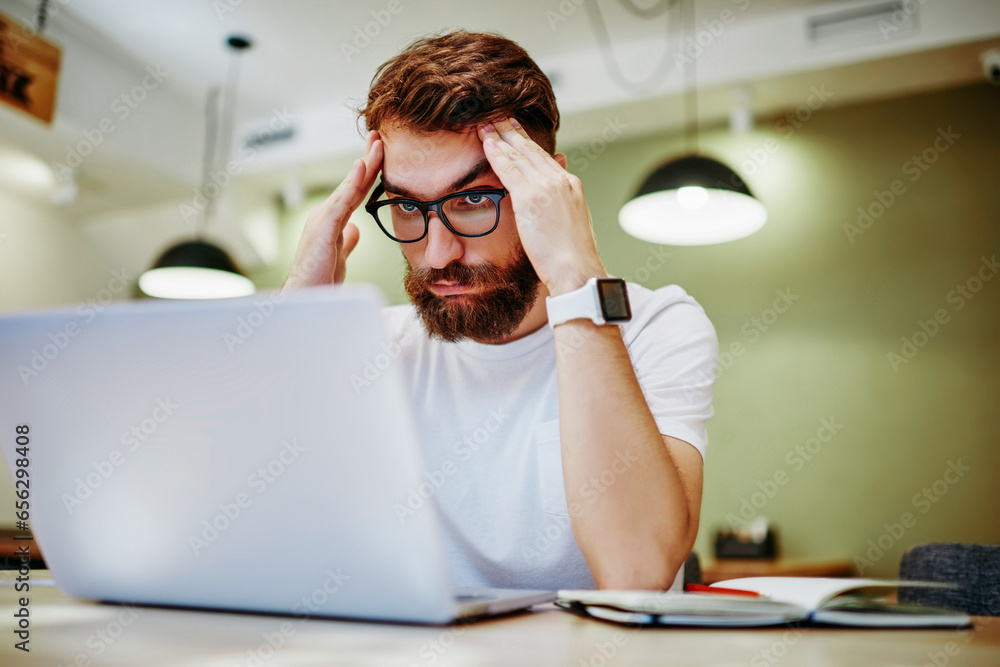 Poster tired hipster guy feeling headache because of problems with online project on netbook