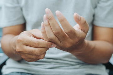 Asian Indonesian man massaging his finger caused by injury or pain