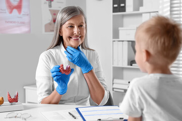 Fototapeta premium Endocrinologist showing thyroid gland model to little patient at table in hospital
