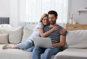 Obraz premium Happy couple with laptop on sofa at home