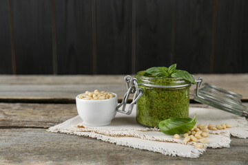 Delicious pesto sauce, pine nuts and basil leaves on wooden table. Space for text