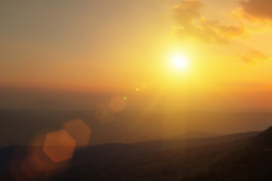 Natural fog and mountains sunlight background blurring, misty waves warm colors and bright sun light. Christmas background sky sunny color orange light patterns, abstract flare evening on clouds blur.