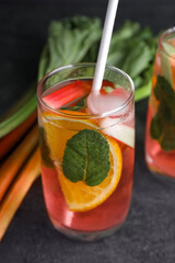 Glass of tasty rhubarb cocktail with lemon on grey table, closeup