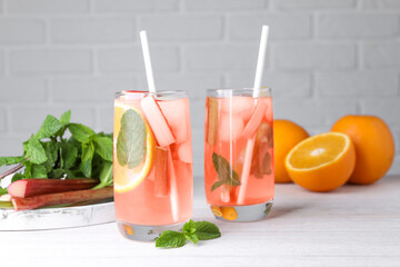 Tasty rhubarb cocktail with orange on white wooden table