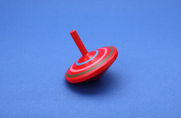 One bright spinning top on blue background. Toy whirligig