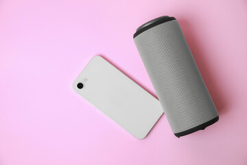 Portable bluetooth speaker and smartphone on pink background, flat lay with space for text. Audio...