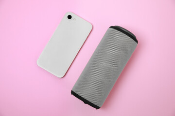 Portable bluetooth speaker and smartphone on pink background, flat lay. Audio equipment