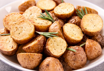 Delicious baked potatoes with rosemary on a gray background
