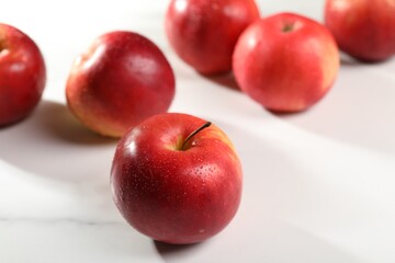 Fresh red apples with water drops on white table, closeup